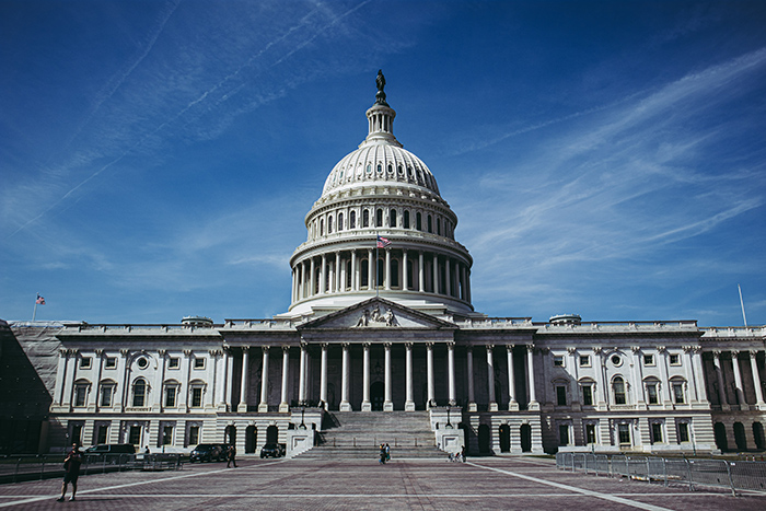 Front view of the US Capitol building with bright blue sky