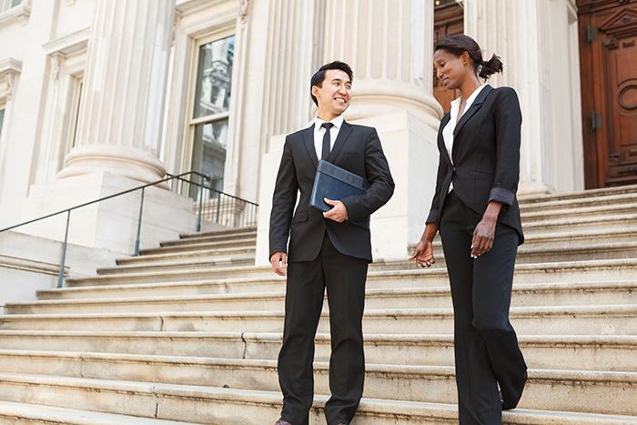 Professionally dressed man and woman walking down government building steps