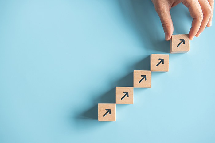 Hand stacking arrows facing upward against a blue background