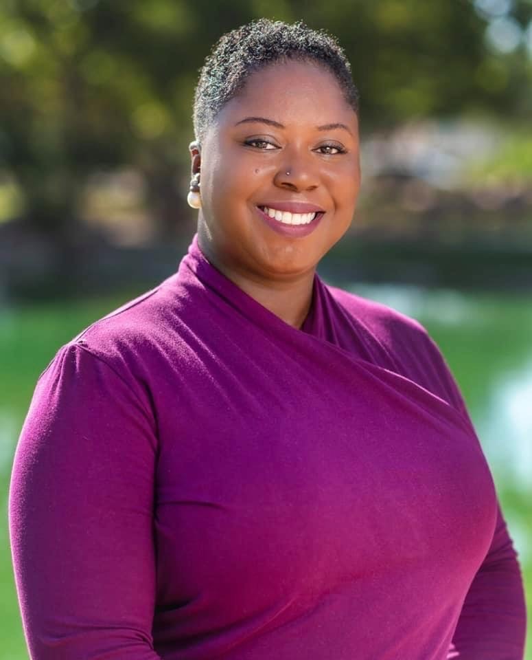 Senior female college professor smiling while talking to class full of students
