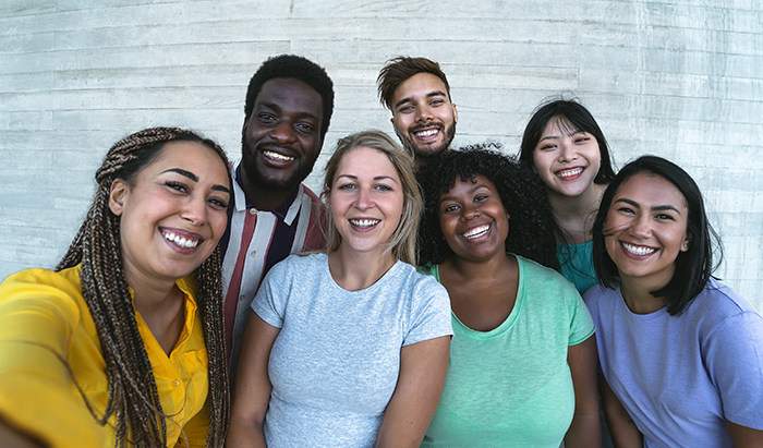 Diverse group of people talking a selfie in front of a white brick wall