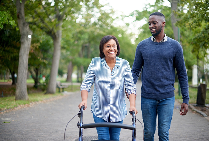 Man and senior woman using a walker outside walking down the street