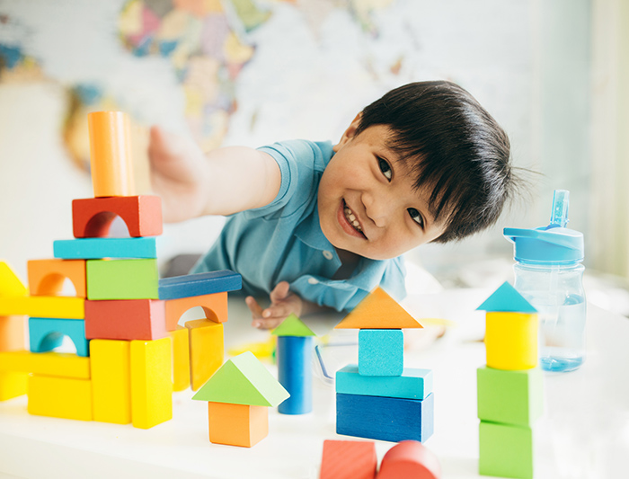Smiling young boy laying on the floor playing with building blocks