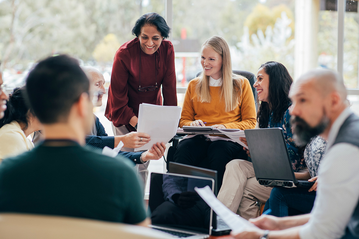 Large diverse group of people sitting in a circle sharing notes and resources together