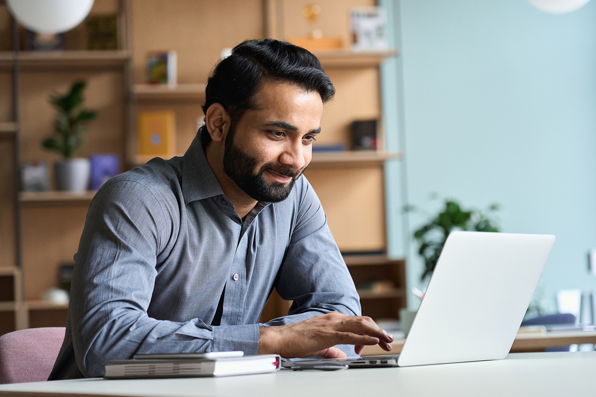 Man sitting at desk typing on an open laptop