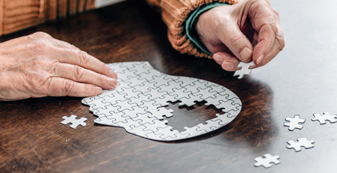 Person putting together a puzzle of an outline of a head